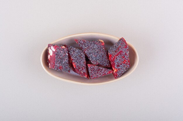 Sweet red candies with nuts in beige bowl on white background. High quality photo