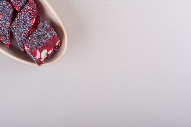 白い背景の上のベージュのボウルにナッツと甘い赤いキャンディー。高品質の写真