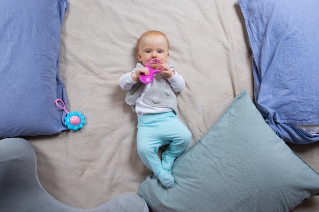 枕の間で毛布の上に横たわる甘い赤い髪の赤ちゃん