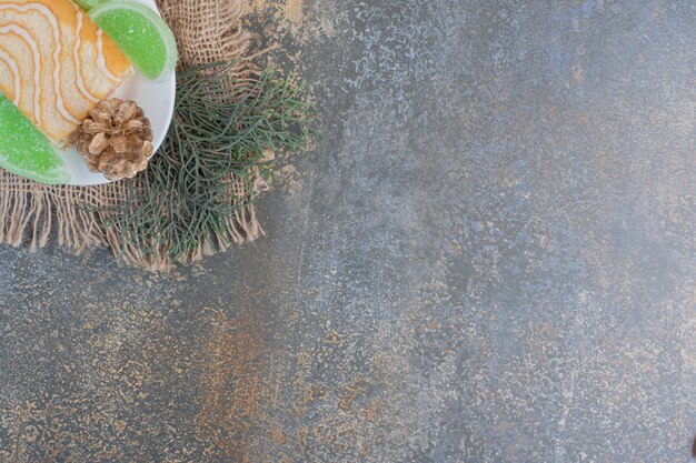 Sweet roll with green marmalades and pinecones on a white plate. High quality photo