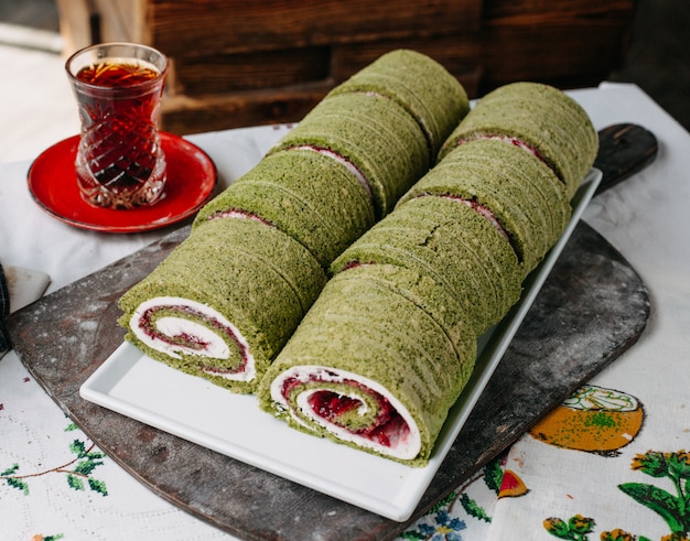 Foto gratuita panini dolci deliziosi progettati con polvere verde rossa all'interno per il tè caldo all'interno del piatto bianco