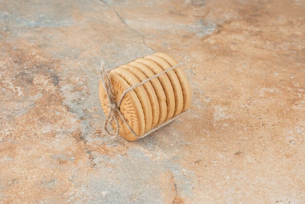 Sweet round cookies in rope on marble background