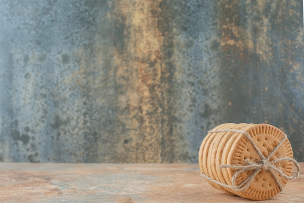 Sweet round cookies in rope on marble background