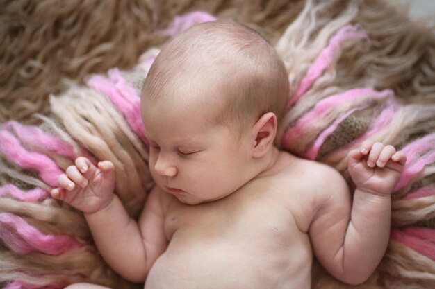 ピンクベージュの毛皮のウールの甘い眠っている新生児