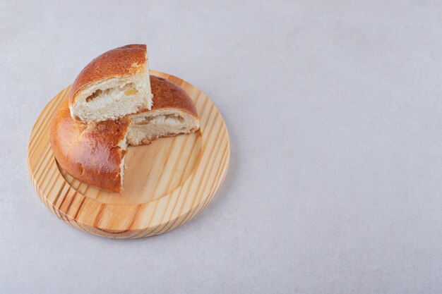 Sweet sliced bun on wooden plate, on the marble.
