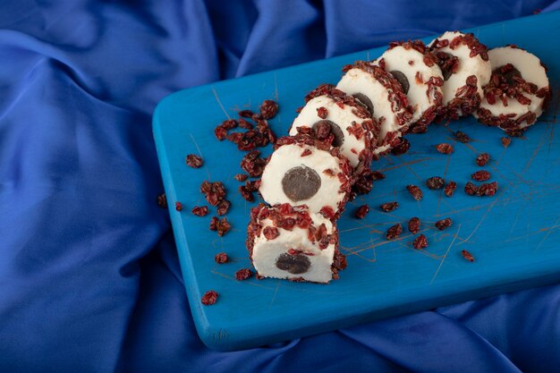 Sweet sliced dessert with dried fruit on a wooden blue board. 