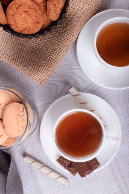 Sweet snacks, cup of tea on light background