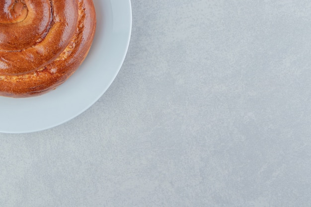 Sweet swirl bun on white plate.