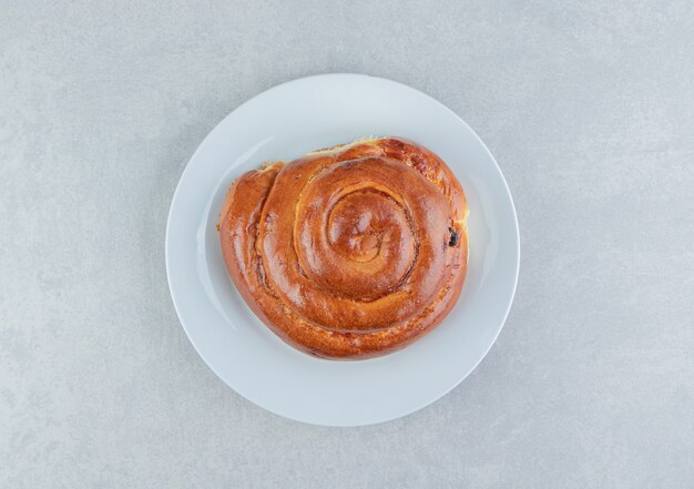 Sweet swirl bun on white plate.