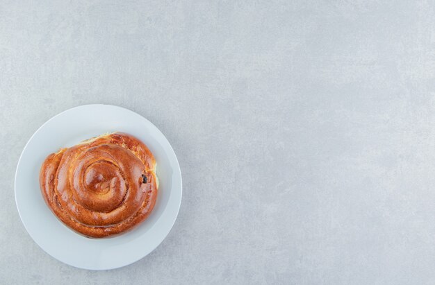 Sweet swirl bun on white plate.