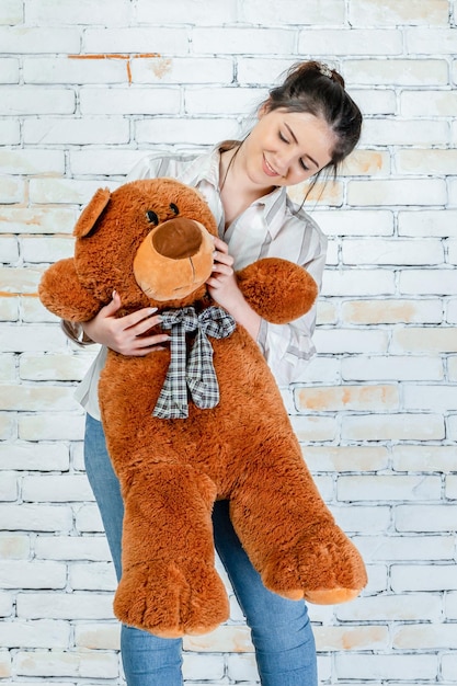 Free photo sweet teddy bear and happy girl on grey background high quality photo