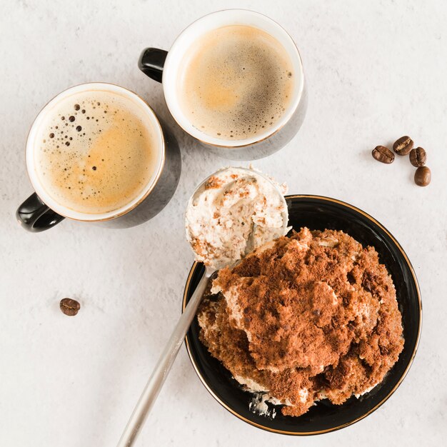 Sweet tiramisu on white table with coffee