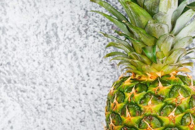 Free photo sweet whole pineapple on grunge surface, close-up.