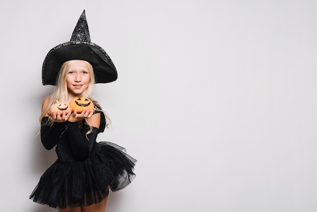 Free photo sweet witch showing jack-o-lanterns