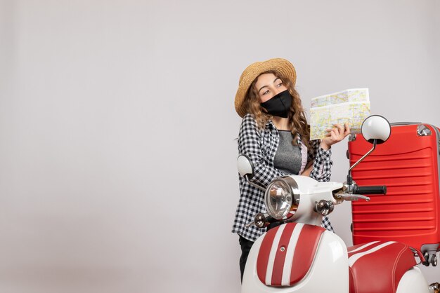 sweet young girl with black mask holding map standing near red moped