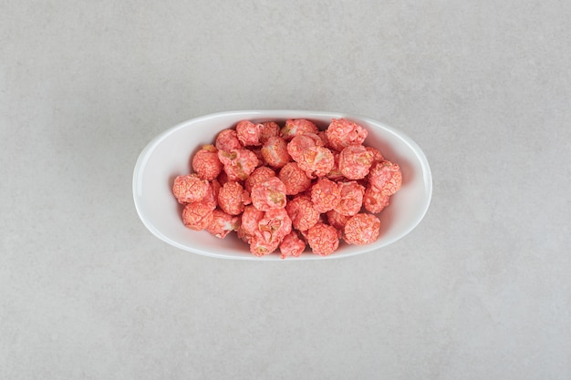 Sweetened popcorn in an oval bowl on marble.