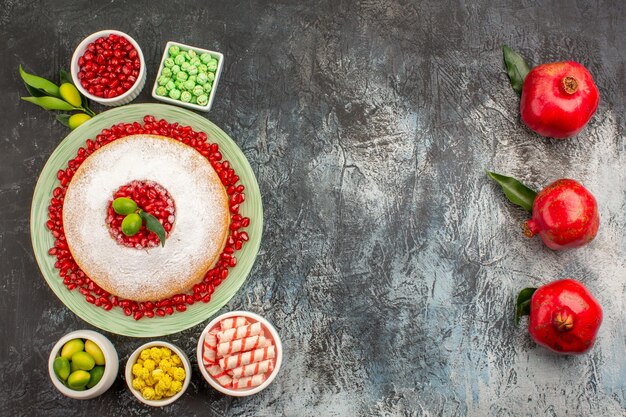 sweets a plate of cake bowls of candies and limes next to the red pomegranates