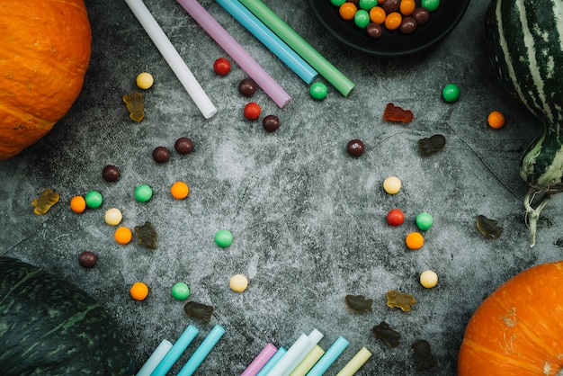 Sweets and straws near pumpkins