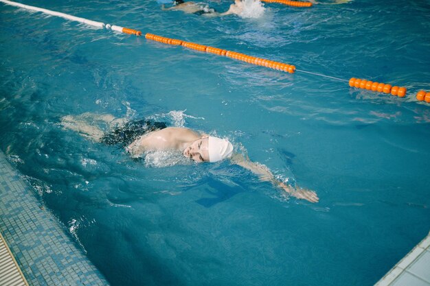 Swimmer in cap training in the pool. Top view from pool side.