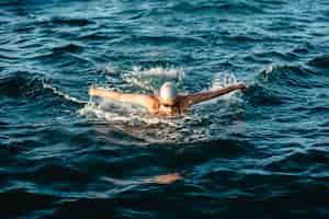 Бесплатное фото Пловец с кепкой и очками плавает в воде