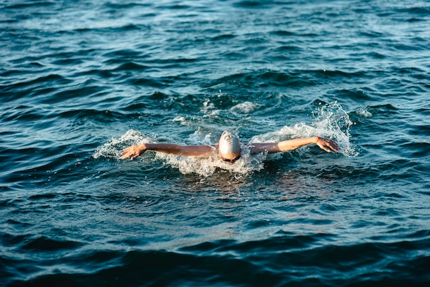 물에서 수영하는 모자와 고글을 착용 한 수영