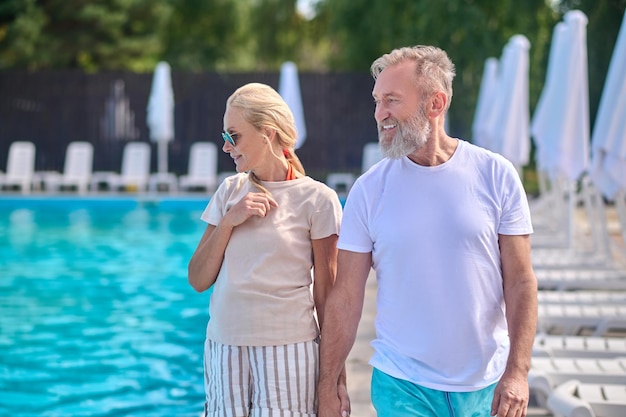 Swimming pool. A man and a woman walking along the swimming pool