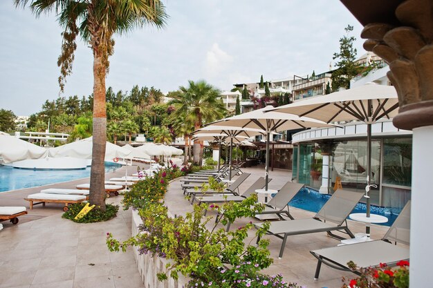 터키 보드룸의 지중해 여름 리조트 호텔에서 아침에 일광욕용 침대가 있는 수영장