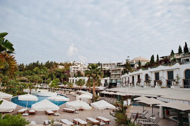 터키 보드룸의 지중해 여름 리조트 호텔에서 아침에 일광욕용 침대가 있는 수영장