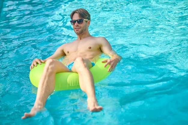 Swimming pool. Young man with a yellow tube in a swimming pool