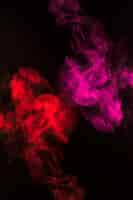 Free photo swirling of red and pink smoke fumes on black background