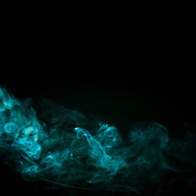 Закрученного бирюзового дыма на черном фоне с копией пространства