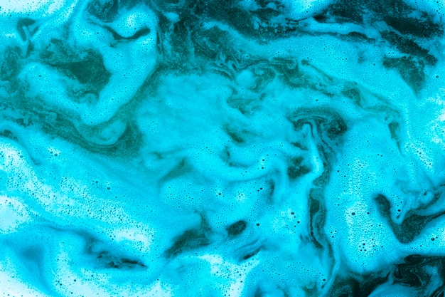 Swirls of foam on blue liquid