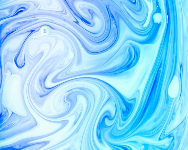 Swirls of paint in blue colored liquid