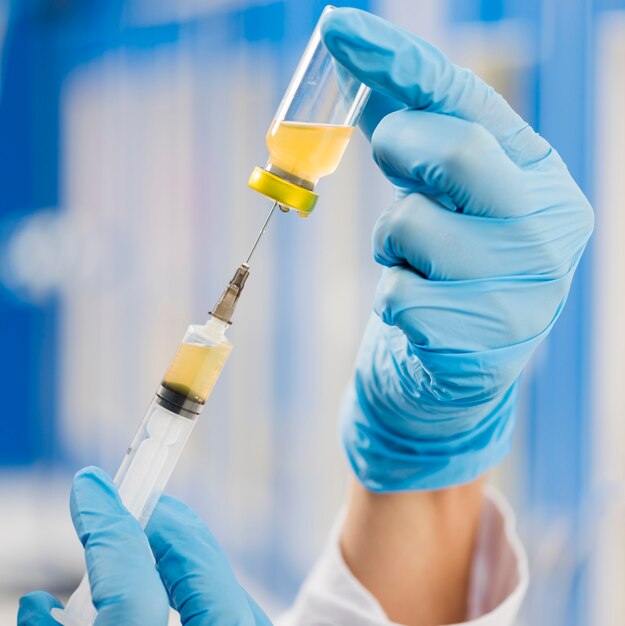 Syringe being filled by scientist with surgical gloves