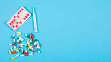 Free photo syringe and colorful capsules on blue background