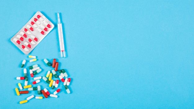 Syringe and colorful capsules on blue background