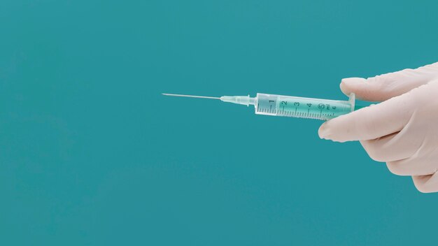 Syringe held by hand with glove and copy space