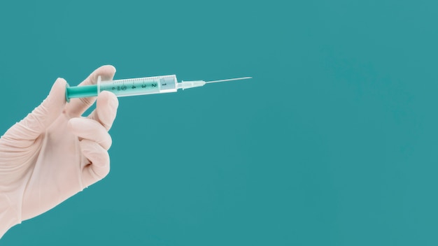 Syringe held by hand with glove and copy space