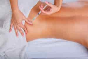 Free photo syringe injection in to woman's back. female enjoing relaxing back massage in cosmetology spa centre.