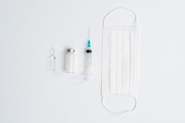 Syringe and mask on white background