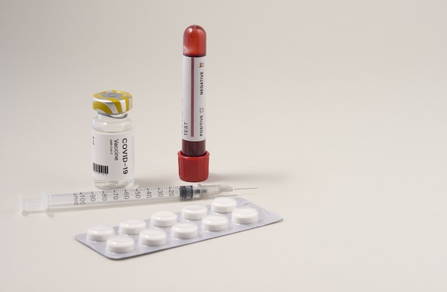 Free photo syringe needle with the vaccine ampoule and a covid-19 test with a tablet pack on the table