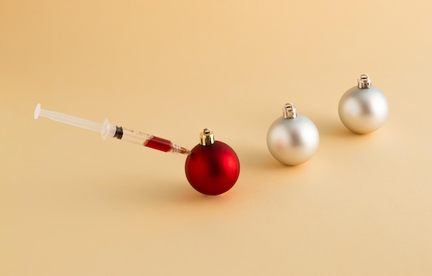 Syringe and vaccination with christmas baubles minimal new year or pandemic idea beauty injections