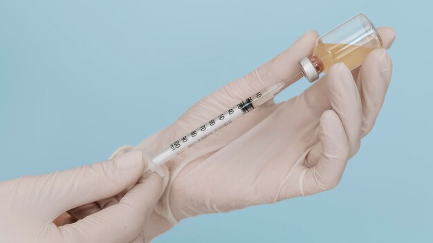 Syringe and vaccine in hands wearing gloves