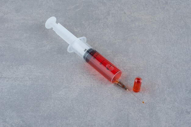 Syringe with blood isolated on gray