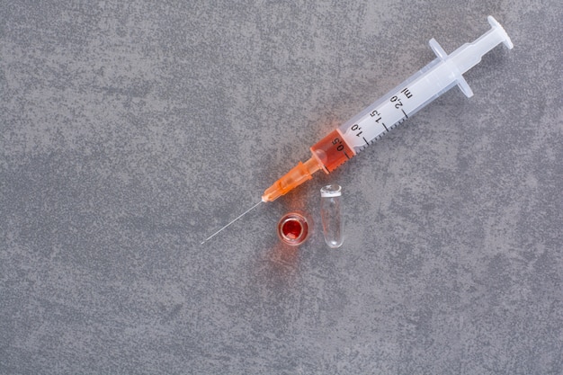 Free photo syringe with red serum on marble table.