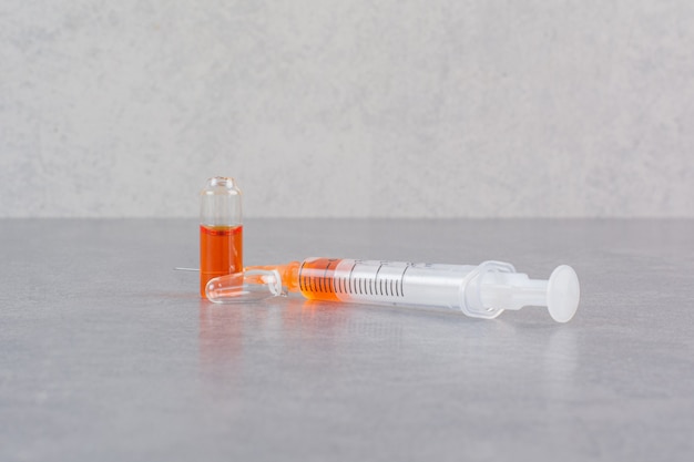 Syringe with red serum on marble table.