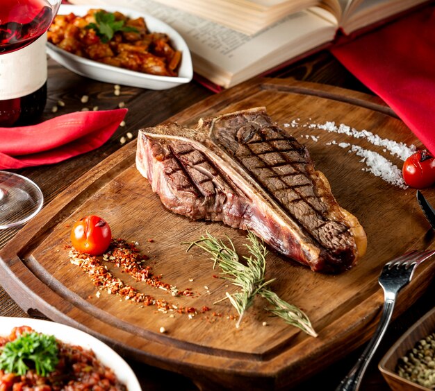 T-bone steak served in wooden board with slat rosemary