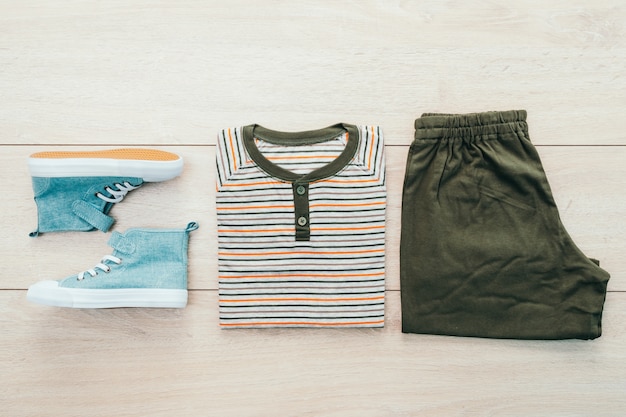 T-shirt with pants and shoes on wooden background