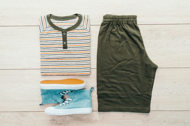 T-shirt with pants and shoes on wooden background