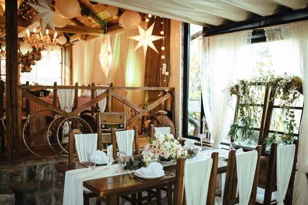 Сервировка стола с цветочным украшением на месте свадебного приема.
